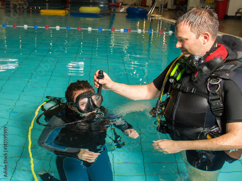 teen girl gets scuba diving lesson from an instructor in a swimming pool scuba diving course