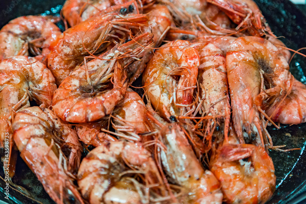 Giant tiger shrimps with heads fried in oil in a frying pan on a gas stove Giant tiger shrimps with heads fried in oil in a frying pan on a gas stove