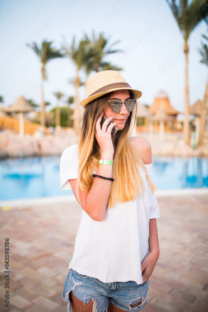 Woman answer on phone call near swiming pool on summer vocation