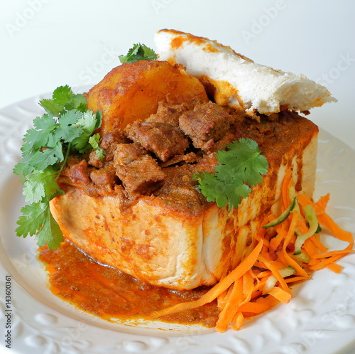 Closeup of lamb "bunny chow" - the popular, Indian fast food cuisine which originated in South Africa, with carrot salad