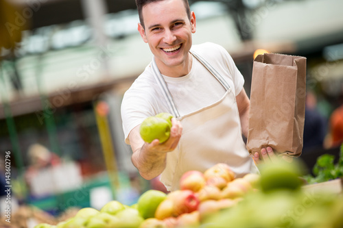 Cuadro en lienzo happy salesman holding apple at a market stall..
