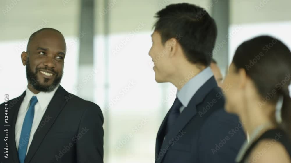 Cheerful business group chatting as they walk through busy modern office Cheerful business group chatting as they walk through busy modern office