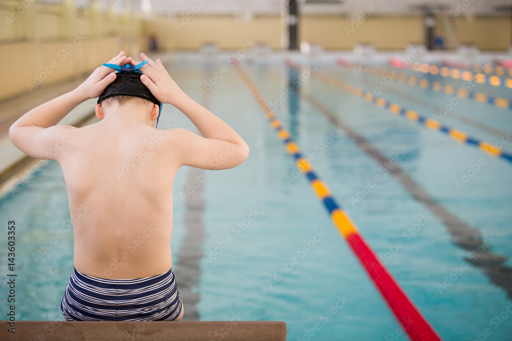 Cute little boy ready to dive in the sport swimming pool. Indoors. Sport activities for children. Training for competition.