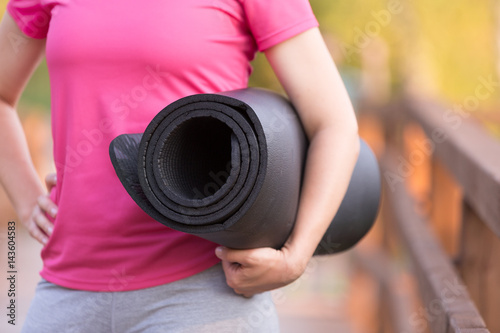 close up of woman's hands holding yoga mat. Girl going to exercise outdoors. Fitness and healthy lifestyle concept © goodmoments