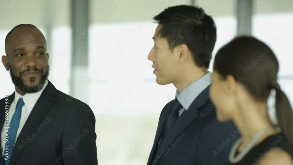 Cheerful business group chatting as they walk through busy modern office Cheerful business group chatting as they walk through busy modern office