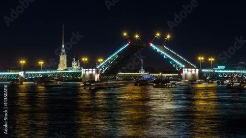 Night view on the Peter and Paul fortress and the Palace bridge lifting, boats floating along the Neva under the open bridge. Saint-Petersburg, Russia. photo