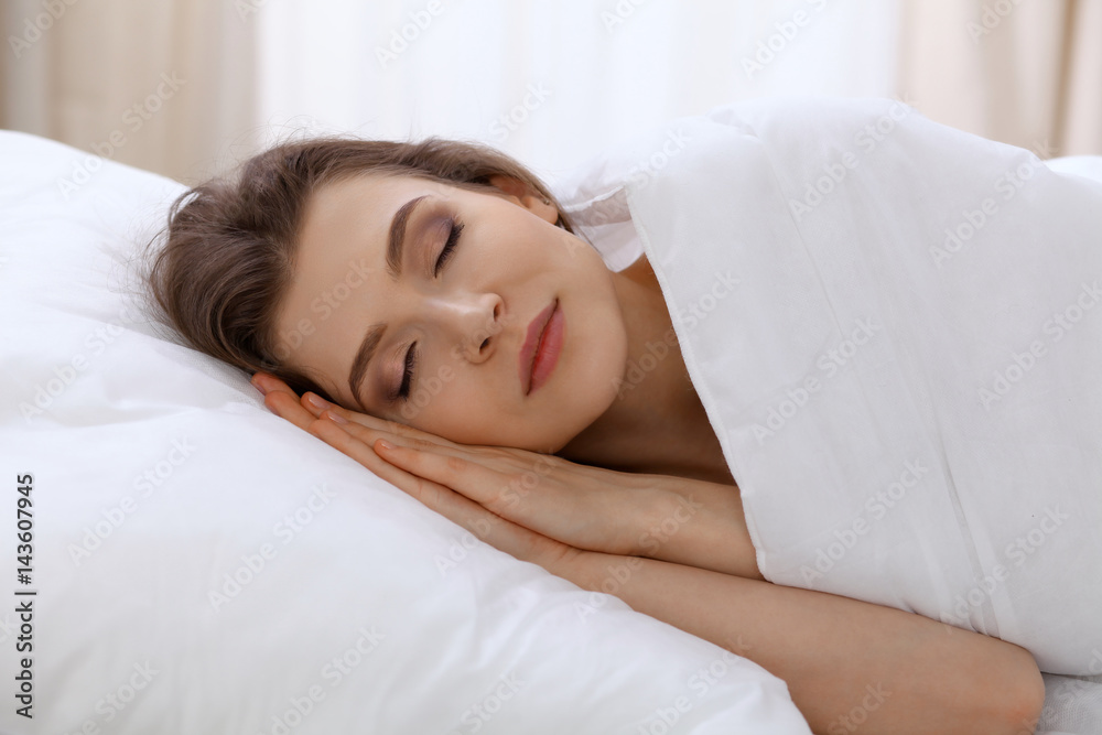 Beautiful young woman sleeping while lying in bed comfortably and blissfully. Early morning, you wake up for work or the day off concept Beautiful young woman sleeping while lying in bed comfortably and blissfully. Early morning, you wake up for work or the day off concept
