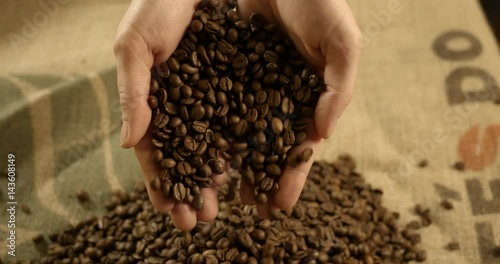 Hands dropping coffee beans on a burlap, slow motion. High quality 4k