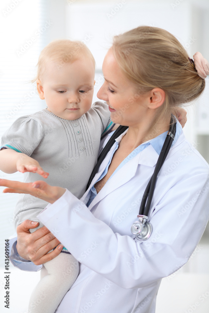 Pediatrician is taking care of patient in hospital. Female doctor holds toddler girl at hands. Health care, insurance and help concept. Pediatrician is taking care of patient in hospital. Female doctor holds toddler girl at hands. Health care, insurance and help concept.