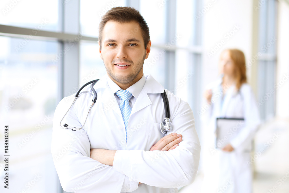 Smiling doctor waiting for his team while standing upright Smiling doctor waiting for his team while standing upright