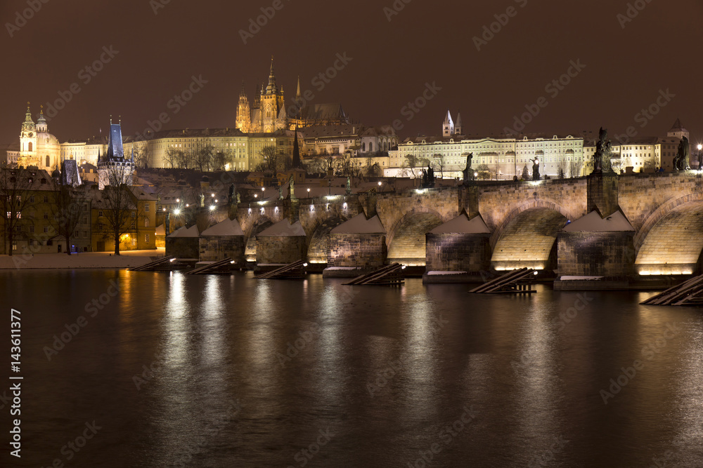 Night snowy Prague Lesser Town with gothic Castle, St. Nicholas' Cathedral and Charles Bridge, Czech republic