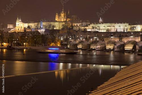 Night snowy Prague Lesser Town with gothic Castle  St. Nicholas  Cathedral and Charles Bridge  Czech republic