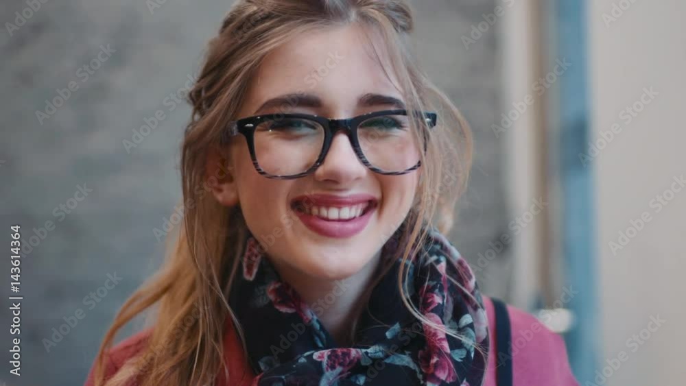 Close up view of gorgeous young girl in a casual outfit looking towards the camera and brightly smiling. Woman in a classical coat and scarf, stylish glasses. Happy moments. Close up view of gorgeous young girl in a casual outfit looking towards the camera and brightly smiling. Woman in a classical coat and scarf, stylish glasses. Happy moments.