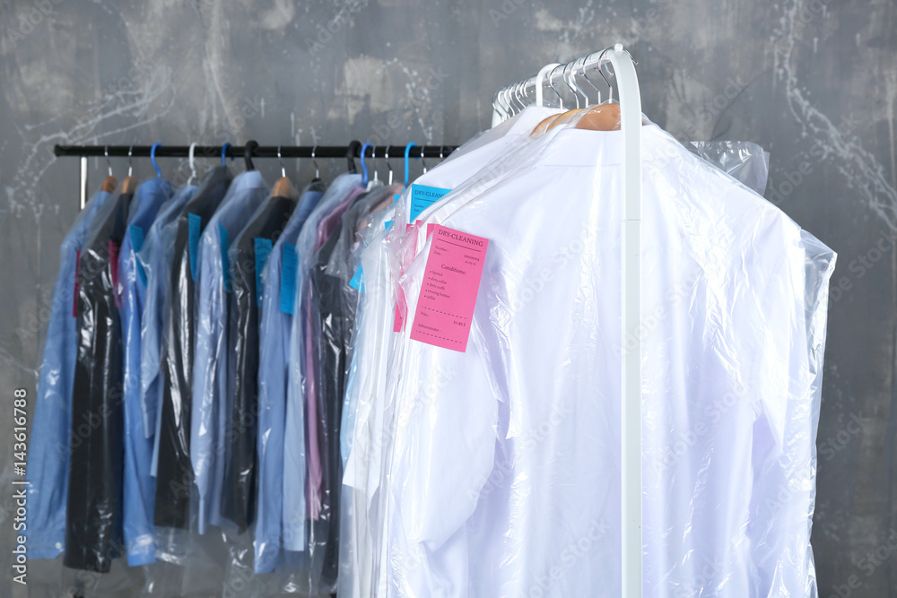 Rack of clean clothes hanging on hangers at dry-cleaning Stock Photo