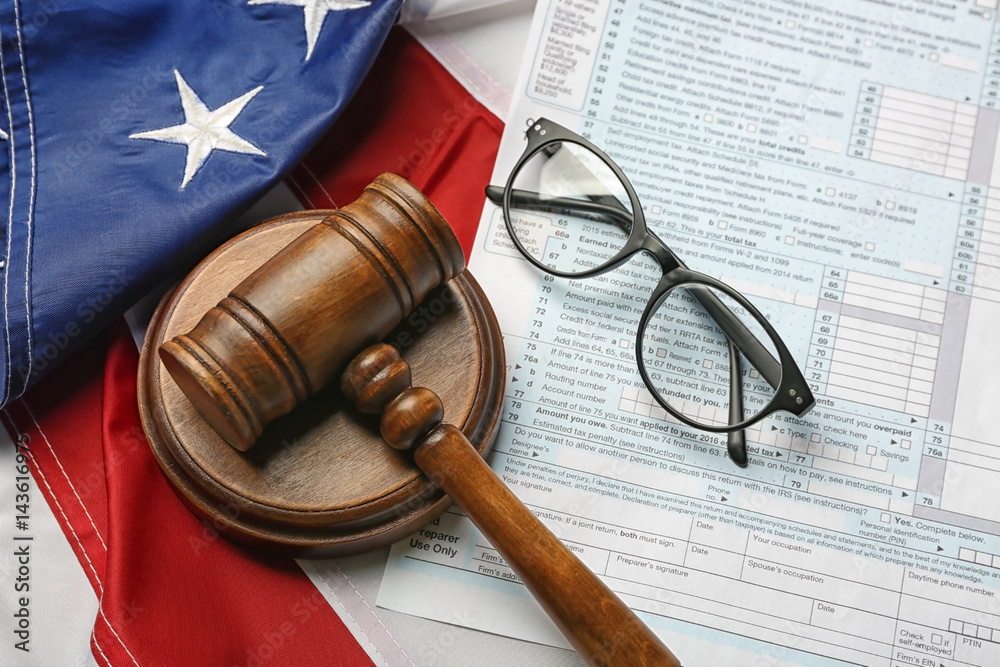 Judge gavel, eyeglasses and tax form on American flag background