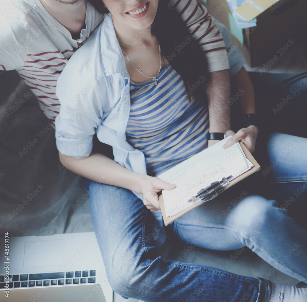 Obraz premium Young couple sitting on the floor of their new apartment