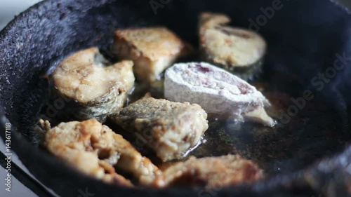 Fish fried in a pan turned with a fork photo