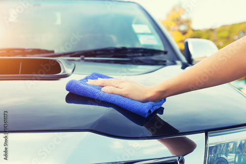 Asian woman's hand wiping surface of car by micro fiber cloth. © DifferR