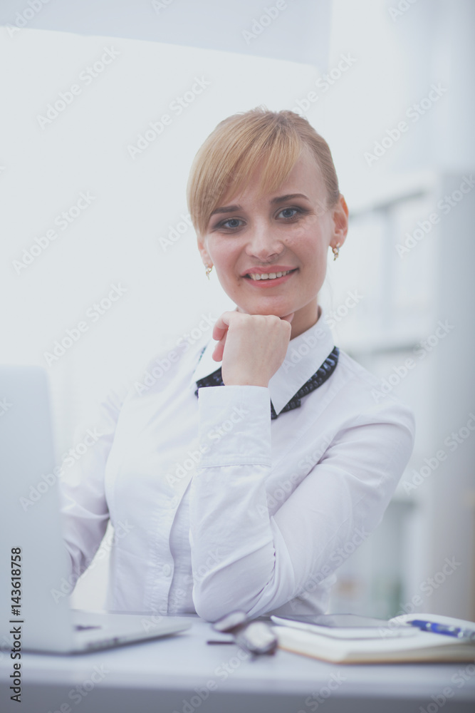 Portrait of businesswoman sitting at desk with a laptop Portrait of businesswoman sitting at desk with a laptop