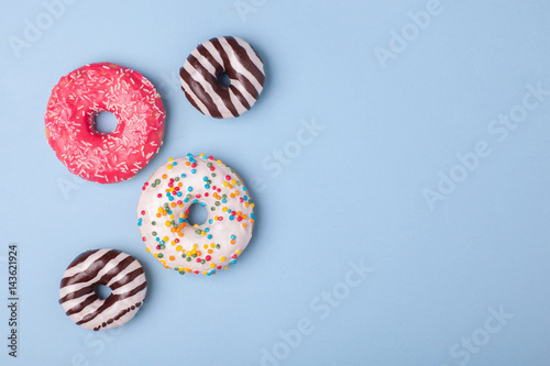 4 sweet glazed donuts with icing on blue background