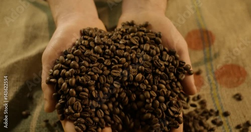 Hands full of roasted coffee beans. Close-up. Slow motion.