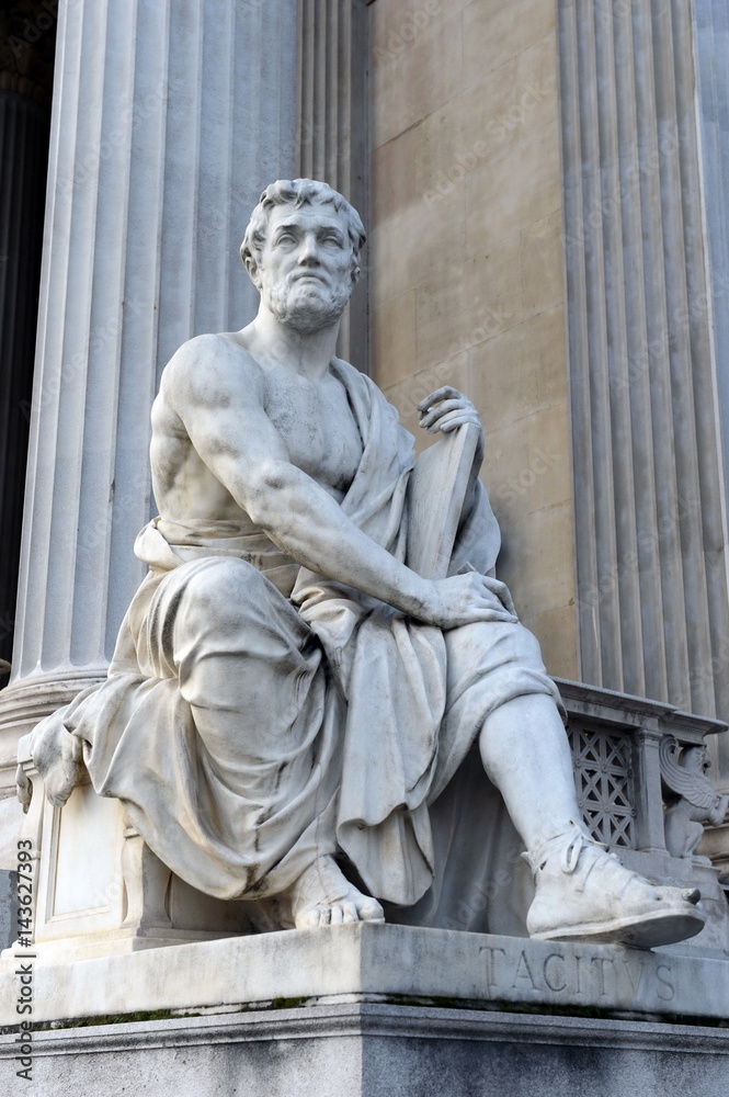 A statue of the Roman historian Tacitus against the building of the Austrian Parliament.