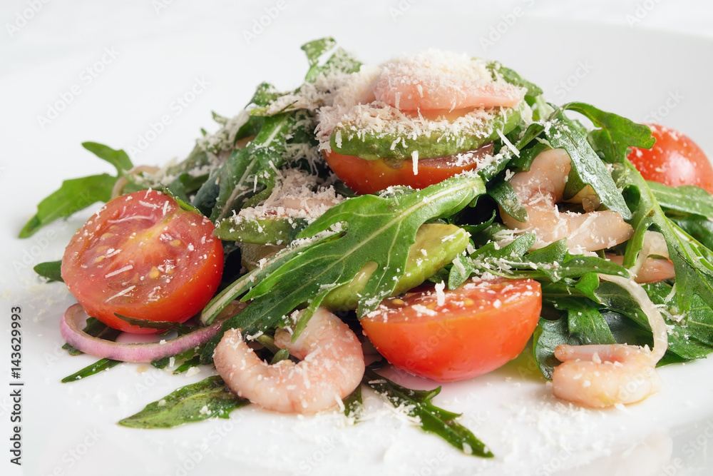 salad of arugula leafs, cherry tomatoes, prawns, avocado, and red onion dressed with olive oil and balsamic vinegar sprinkled with grated parmesan