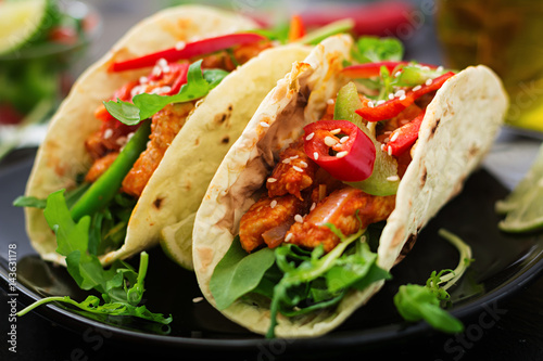 Mexican tacos with chicken fillet in tomato sauce and salsa of paprika and arugula