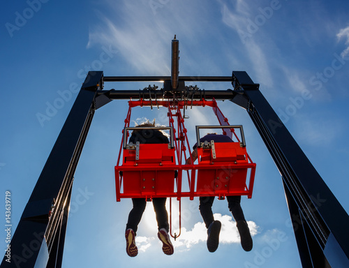 Photography Pair having fun in swing on a high building against blue sky