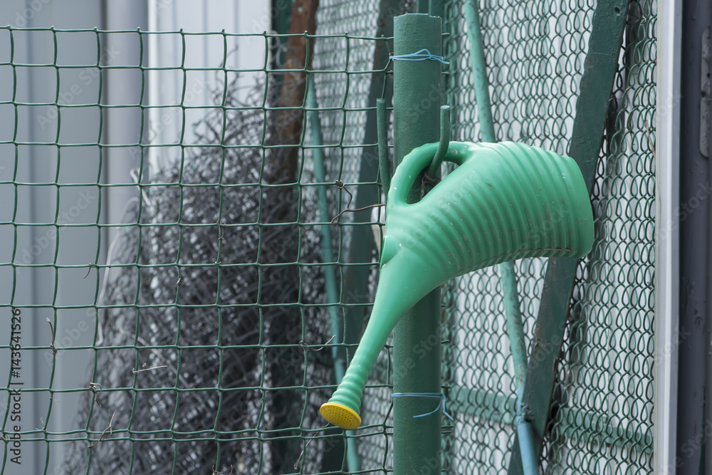 Green watering can hanging on the green hook. Green watering can hanging on the green hook.