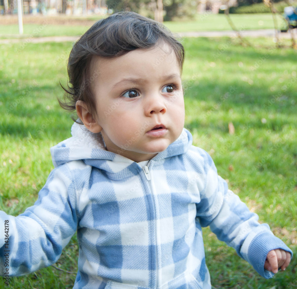 baby in plaid blue overalls in park baby in plaid blue overalls in park