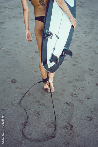 Beautiful girl on a surf board in the ocean. Girl with long hair in a white bathing suit in the ocean on the longboard. beautiful girl with a tattoo on his back in the ocean surf.