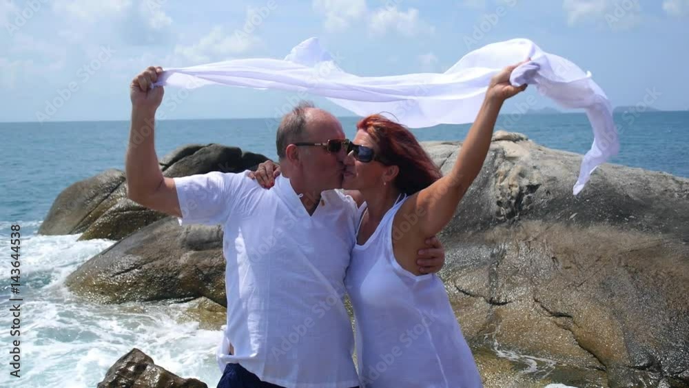 Middle-Aged Couple in White Clothes at Beach on Holidays Middle-Aged Couple in White Clothes at Beach on Holidays