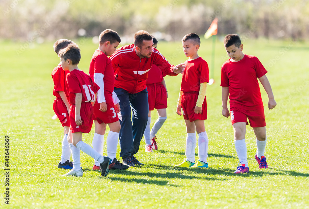 Kids soccer football - children players with coach at match on soccer field