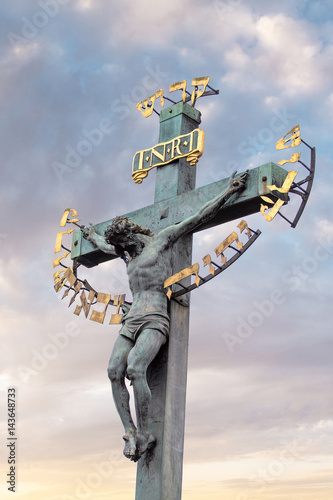 Jesus Christ sculpture on the cross crucifix on dramatic sky background photo