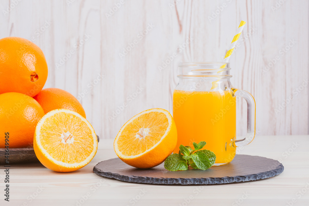 Fresh orange juice in a mason jar and orange sliced ripe on wooden table. Healthy eating concept. Fresh orange juice in a mason jar and orange sliced ripe on wooden table. Healthy eating concept.