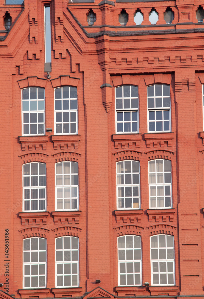 Facade of an old brick red building with windows