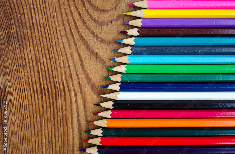 Fototapeta premium Colored pencils on a wooden board background.