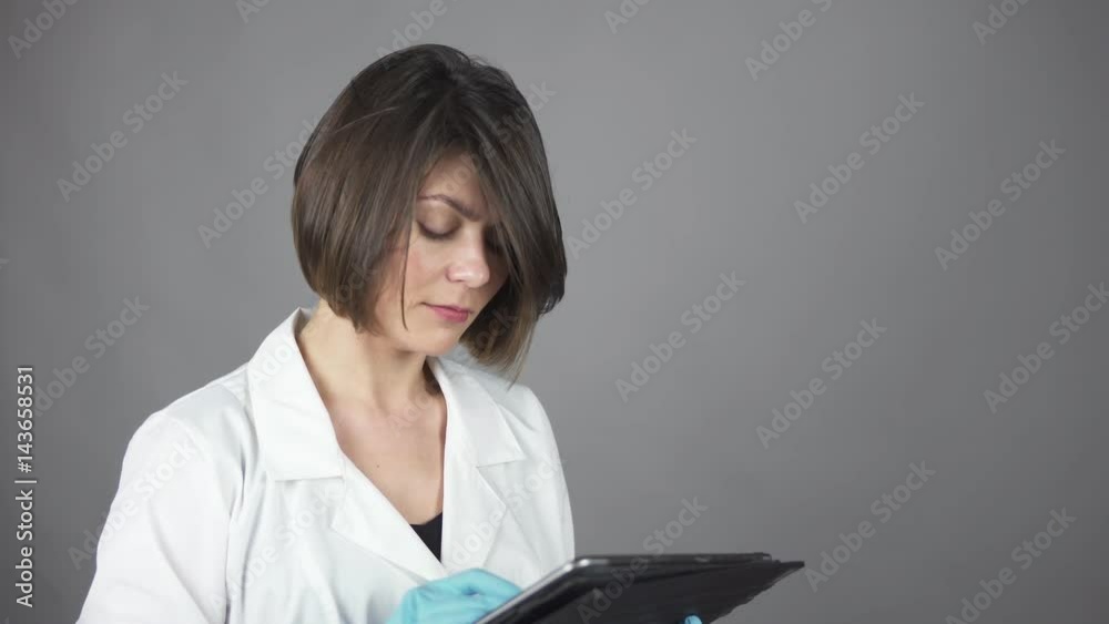 Female doctor in blue rubber gloves using a tablet isolated on grey background. Healthcare concept. Shot in 4k. Female doctor in blue rubber gloves using a tablet isolated on grey background. Healthcare concept. Shot in 4k.