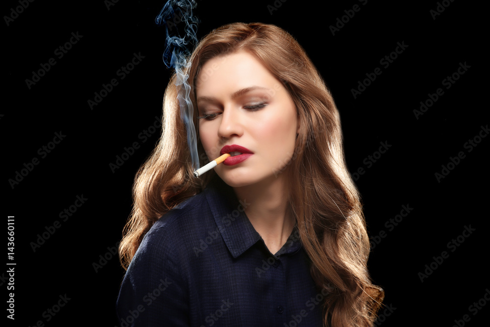 Obraz premium Portrait of beautiful woman with cigarette on black background