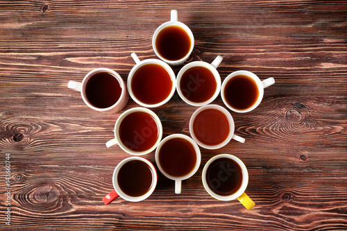 Delicious tea in cups forming star on wooden background