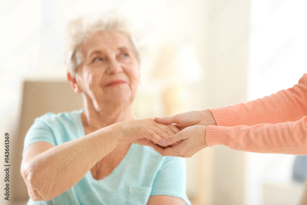 Old and young women holding hands on blurred background, closeup Old and young women holding hands on blurred background, closeup