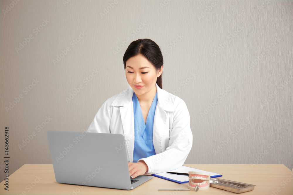 Pretty dentist working on laptop at workplace Pretty dentist working on laptop at workplace