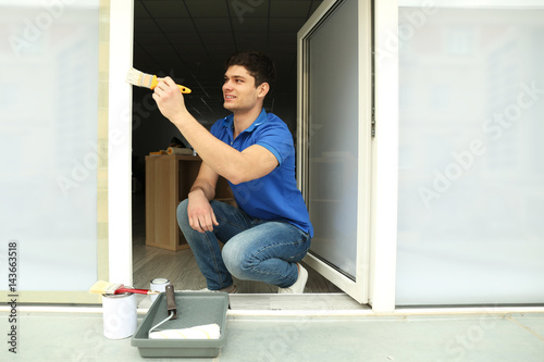Young man painting window a...
