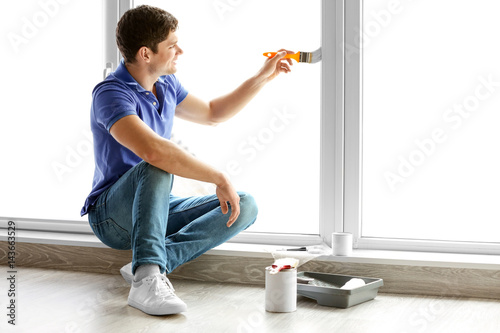 Young man painting window a...