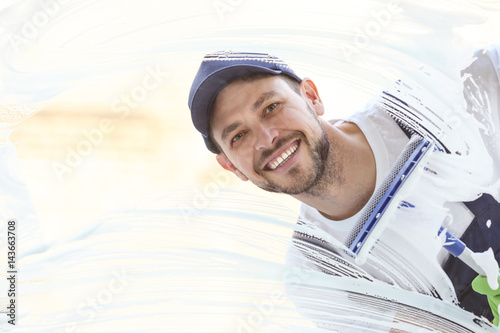 Young man washing window in...