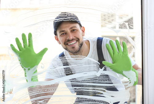 Young man washing window in...