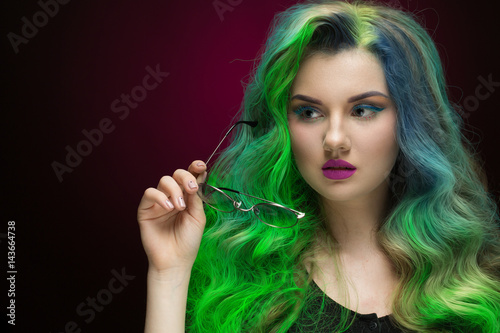 She got her style. Studio portrait of a beautiful green haired young woman looking away thoughtfully holding her glasses copyspace on the side