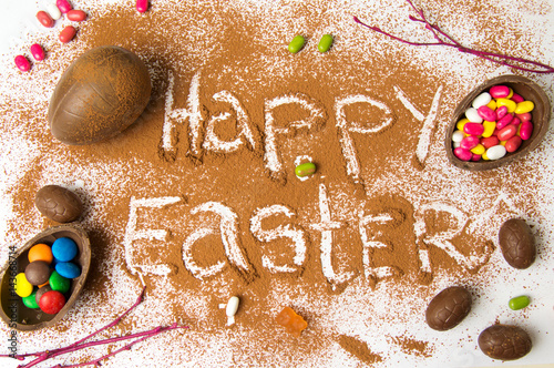 Happy Easter in cacao powder with chocolate eggs