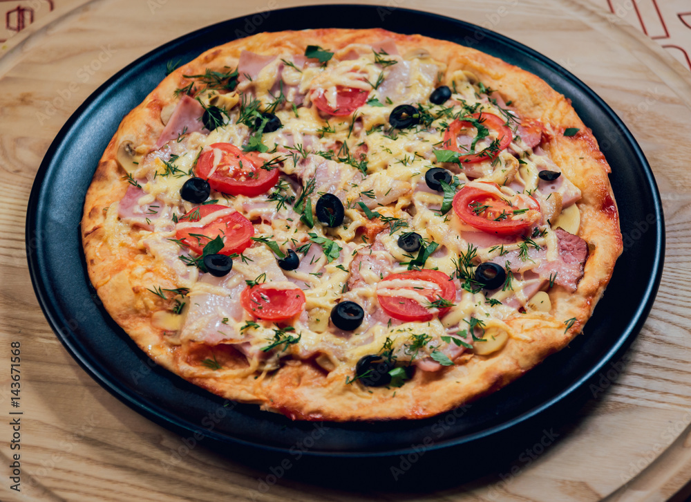 Large hot pizza on the black plate. Large hot pizza on the black plate.